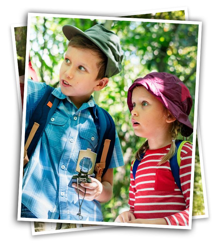 curious kids exploring at summer camp with a compass, wearing hats because they are in a wooded area of Virginia