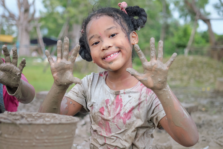 little girl, black, showing off muddy hands and a big smile after getting dirty playing outdoors