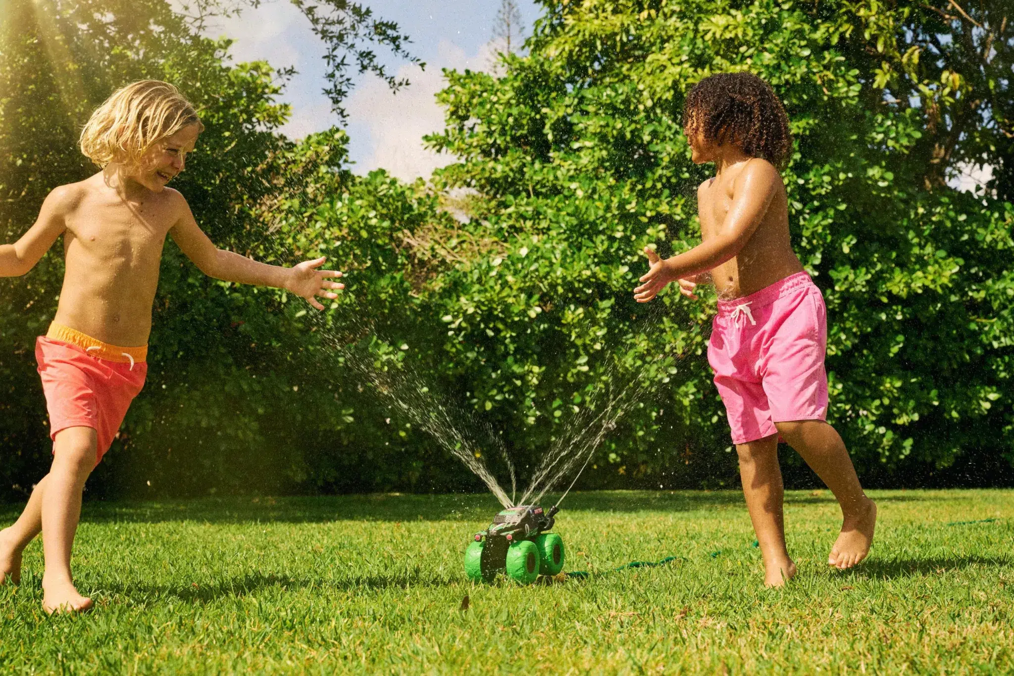 two kid splaying outside in sprinkler