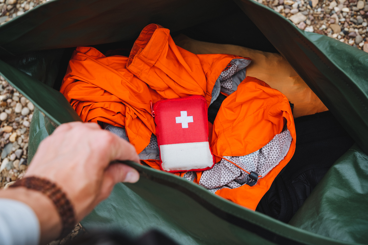 Wellequipped for outdoor adventures, a detailed shot of camping essentials includes vital first aid kit bright orange clothing in a backpack. Ready for emergencies wilderness survival
